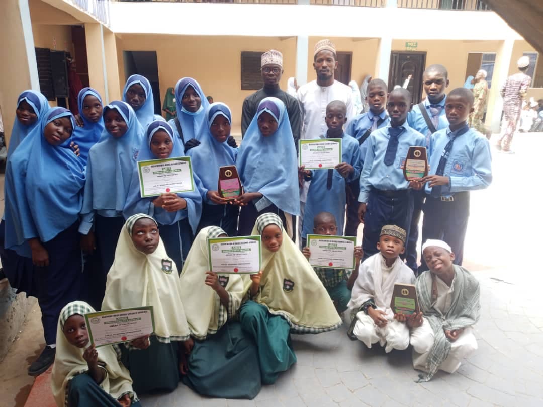 Al-Falaah Academy students in uniform studying in a bright, modern classroom decorated with Quranic calligraphy